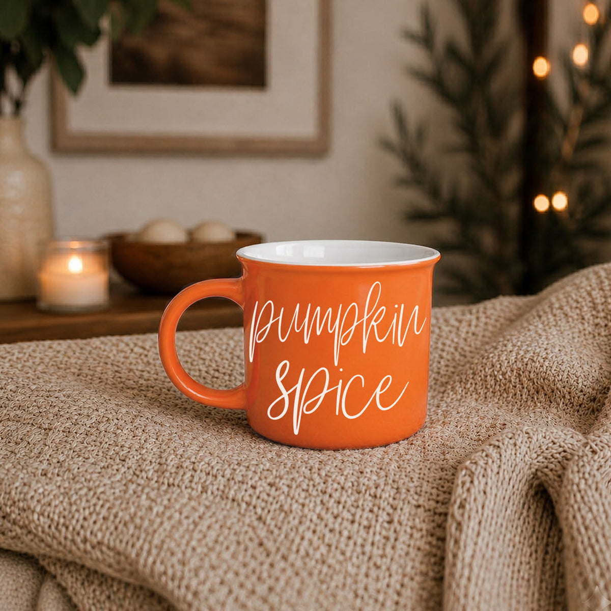 Orange mug with white interior and “Pumpkin Spice” script text on tabletop