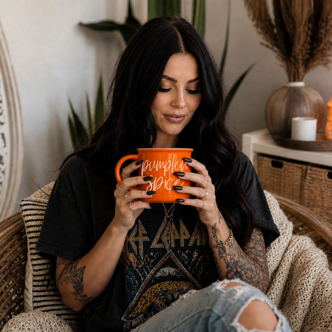 Person holding an orange mug with “Pumpkin Spice” script text