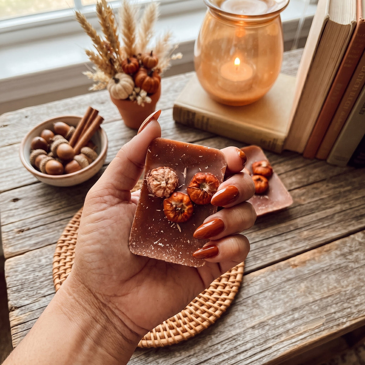 Hand holding an XL pumpkin pecan wax melt square, dark amber with embedded nuts.