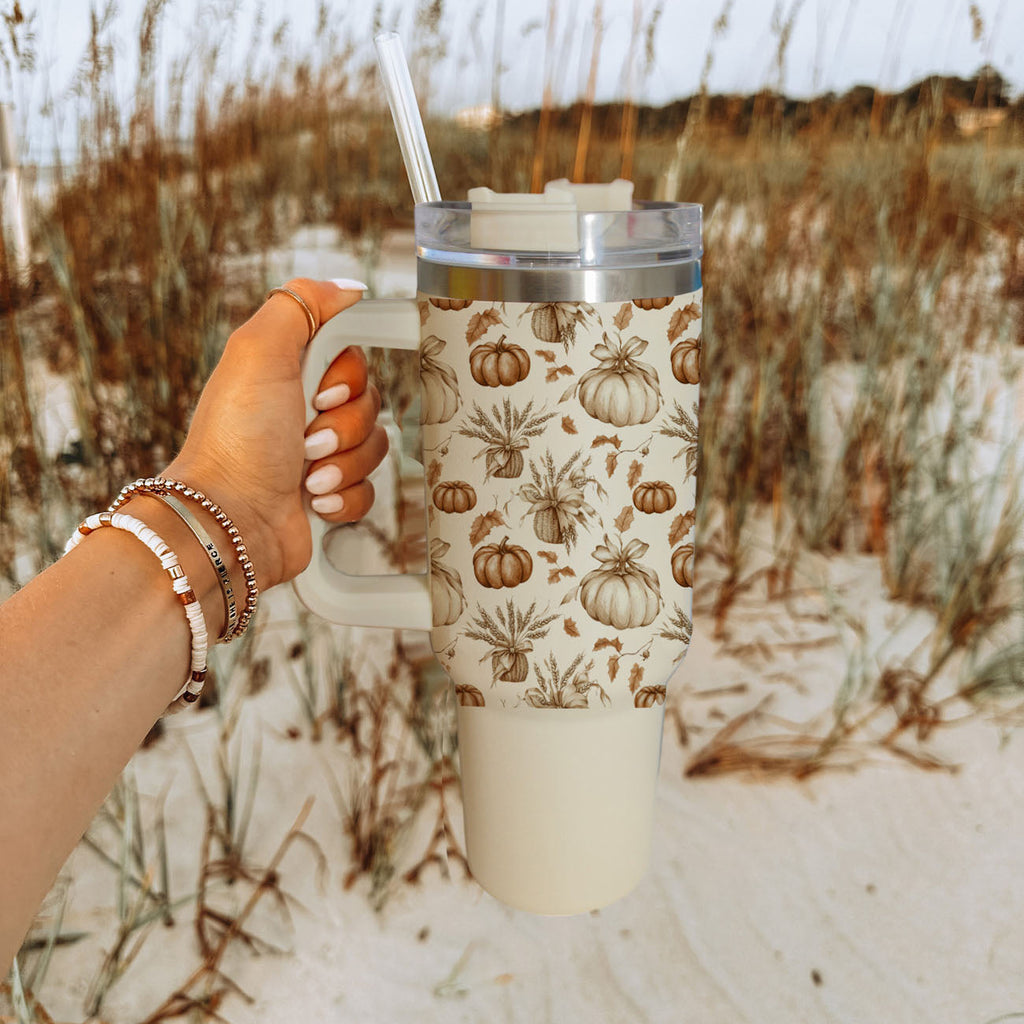 Beige travel mug with handle and straw, clear lid, pumpkin and botanical graphic.