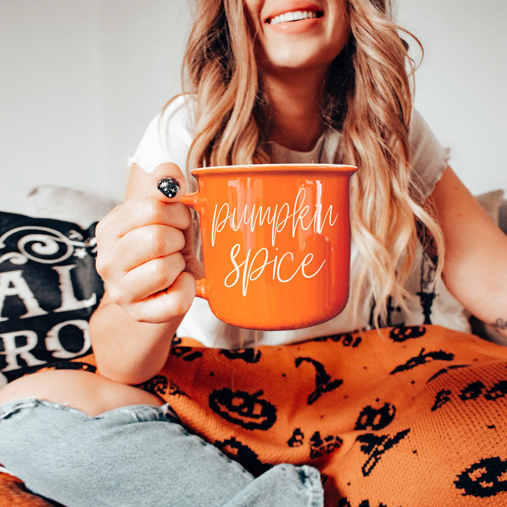 Orange ceramic mug with 'Pumpkin Spice' print, close-up in hands