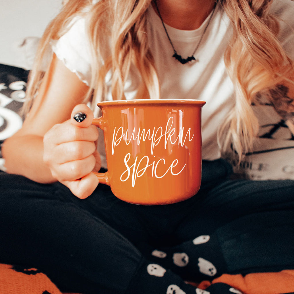 Orange ceramic mug with 'Pumpkin Spice' print, held close to chest