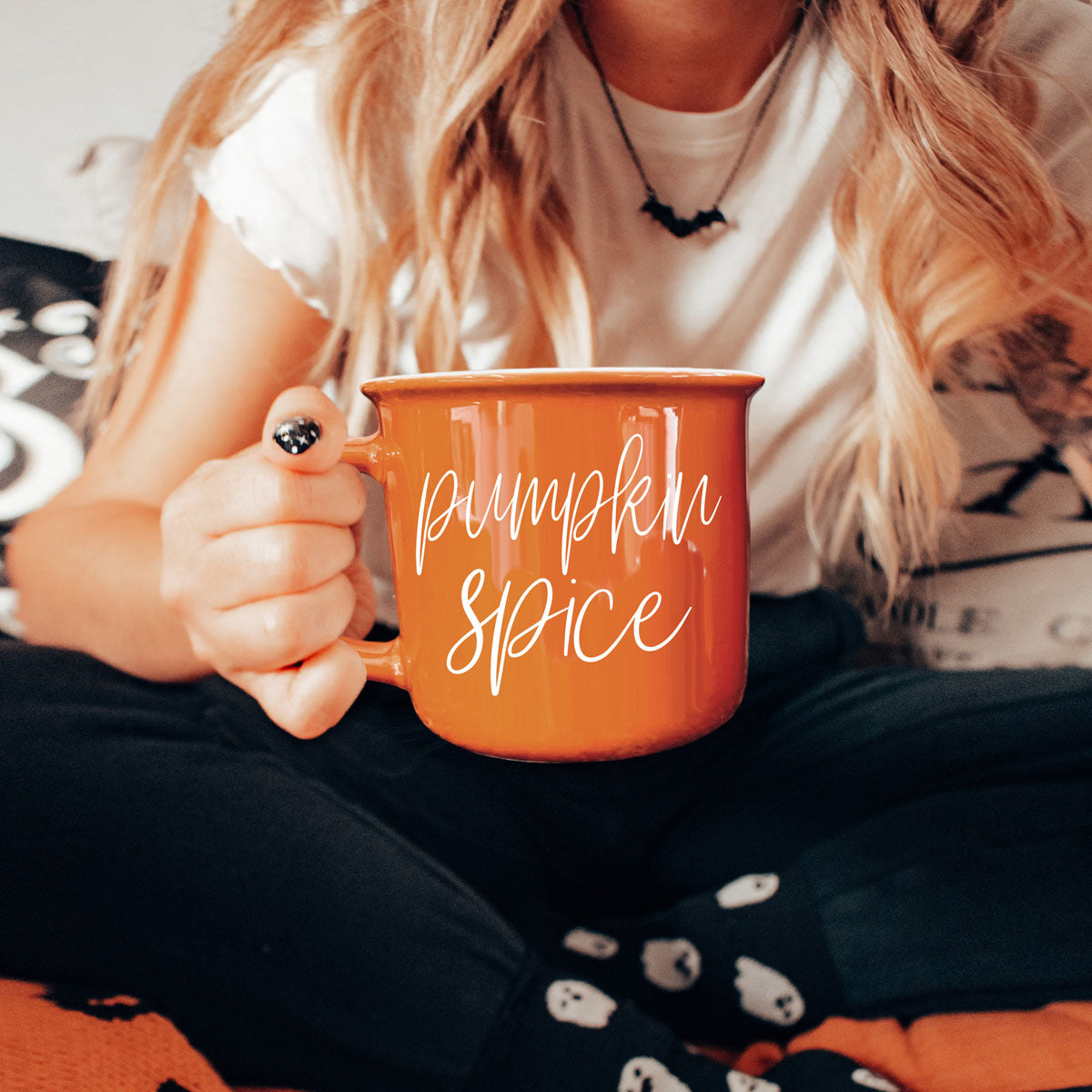 Orange ceramic mug with 'Pumpkin Spice' print, held close to chest