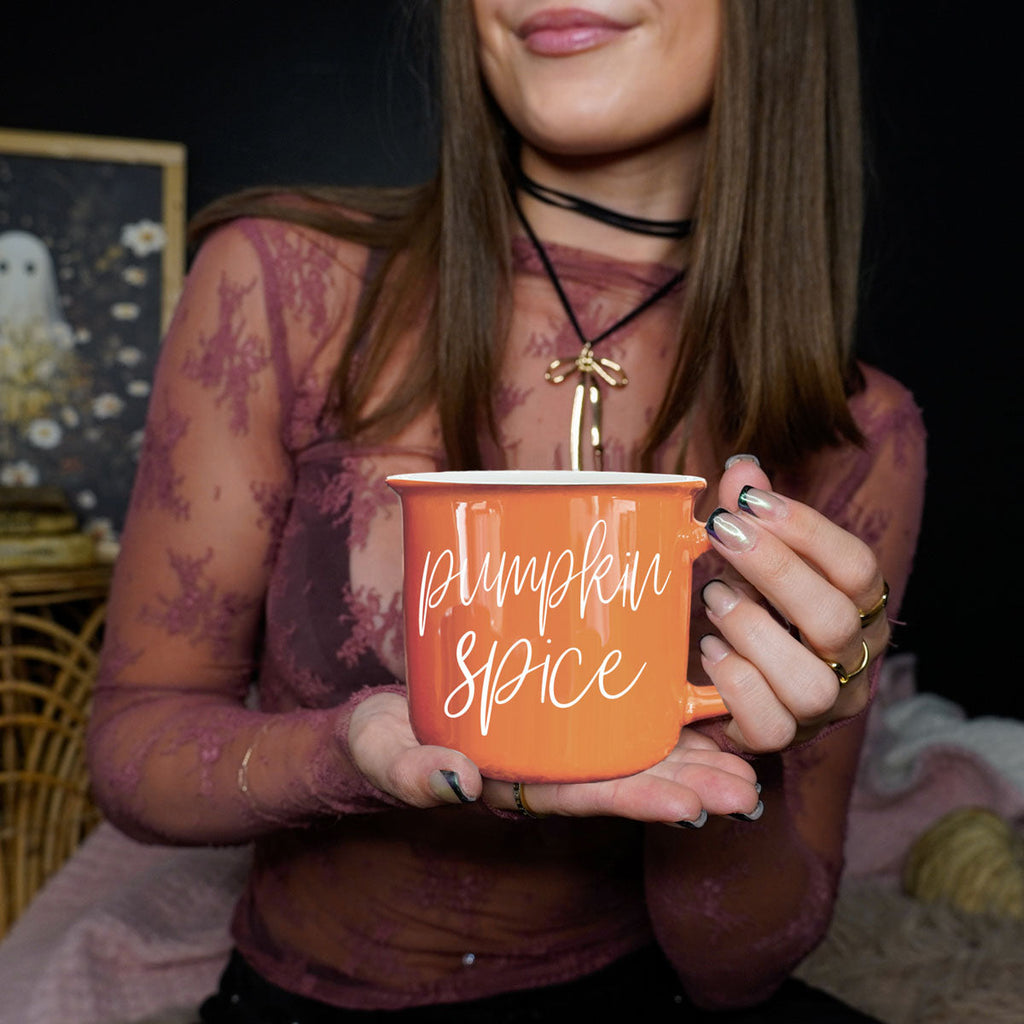 Orange ceramic mug with 'Pumpkin Spice' print, held in hand