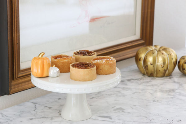 Nora Fleming mini pumpkin spice topper on pedestal: orange pumpkin and white mini