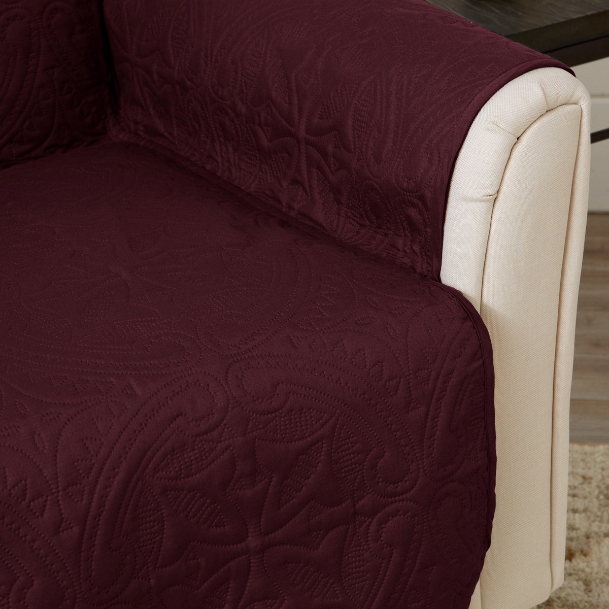 Close-up: burgundy recliner protector with textured medallion pattern on beige arm