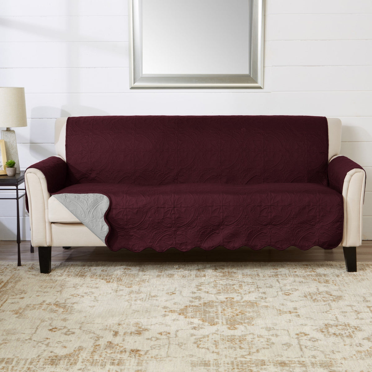 Wine red loveseat protector with quilted fabric and fitted drape over seat and back.