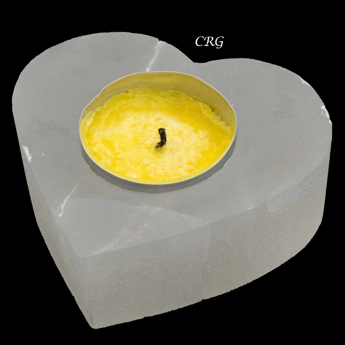 White selenite heart candle holder with yellow tea light in center recess