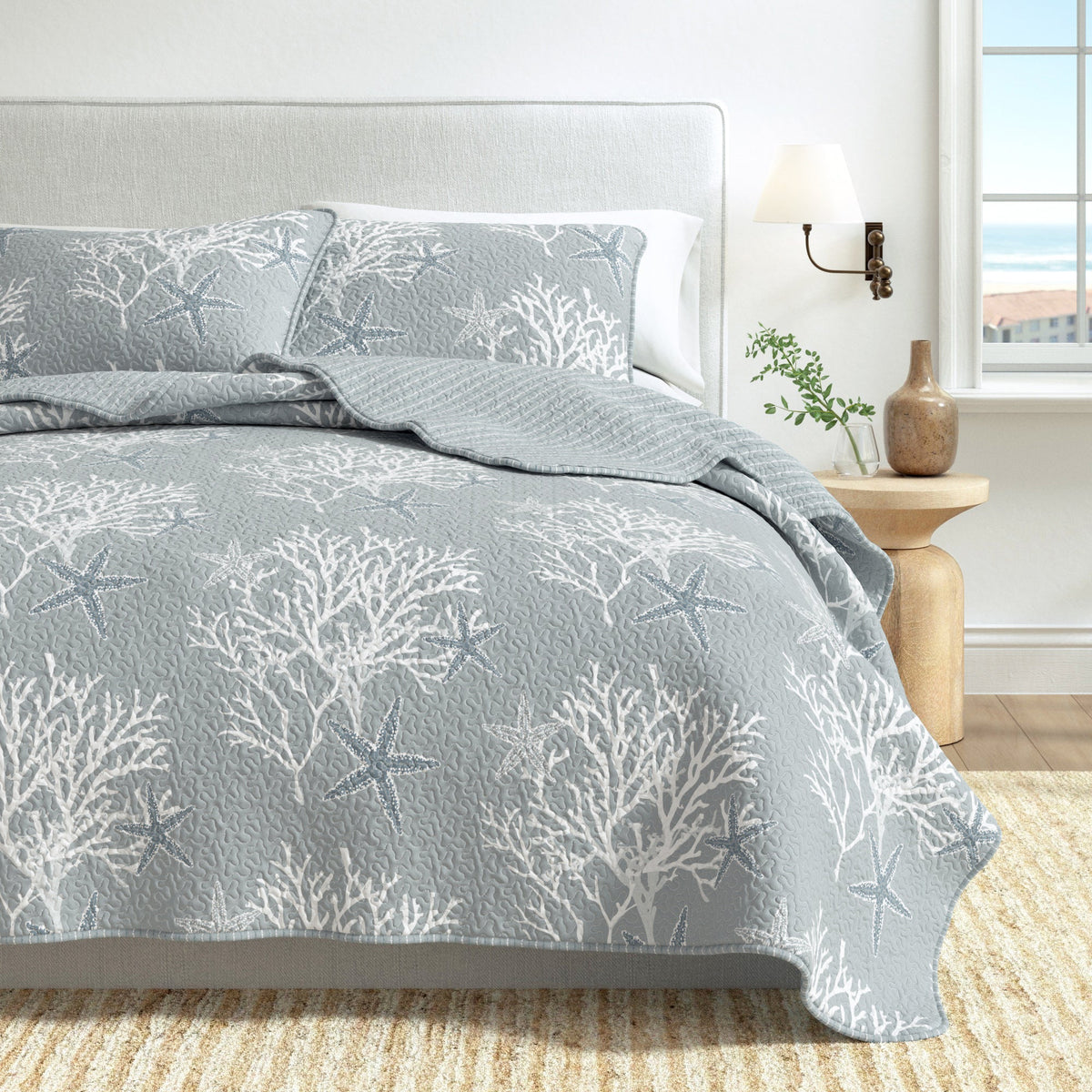 Blue quilt set with starfish and coral print, styled with matching pillow shams.