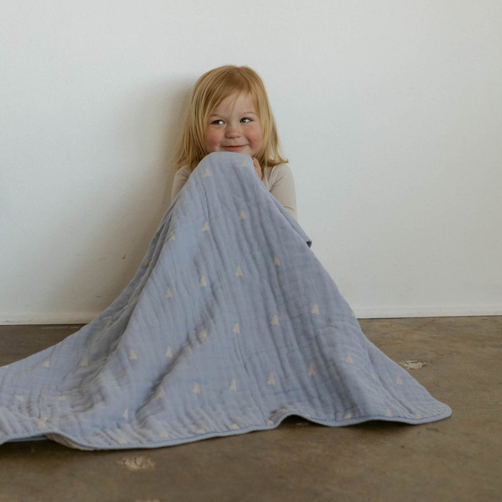 Light blue cloud-pattern muslin quilt draped over a child