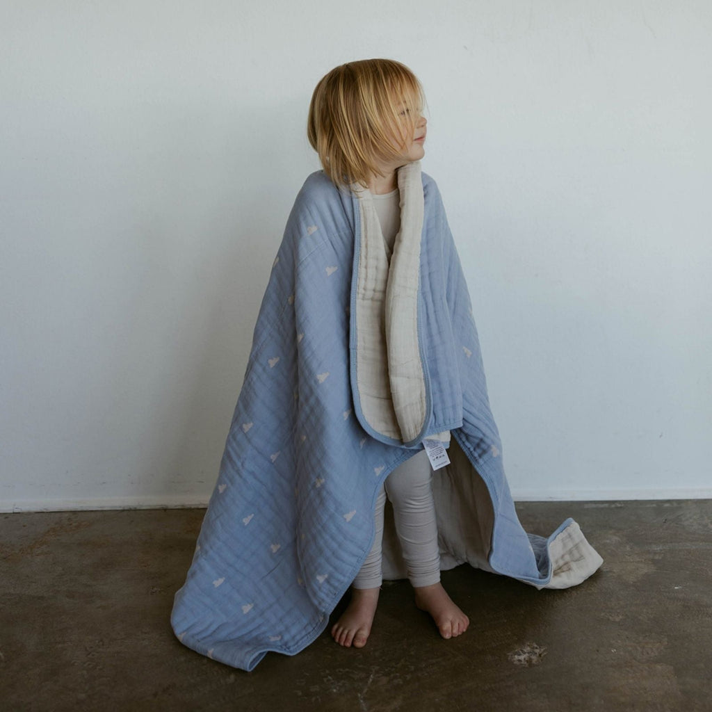 Light blue cloud-pattern muslin quilt wrapped around a child