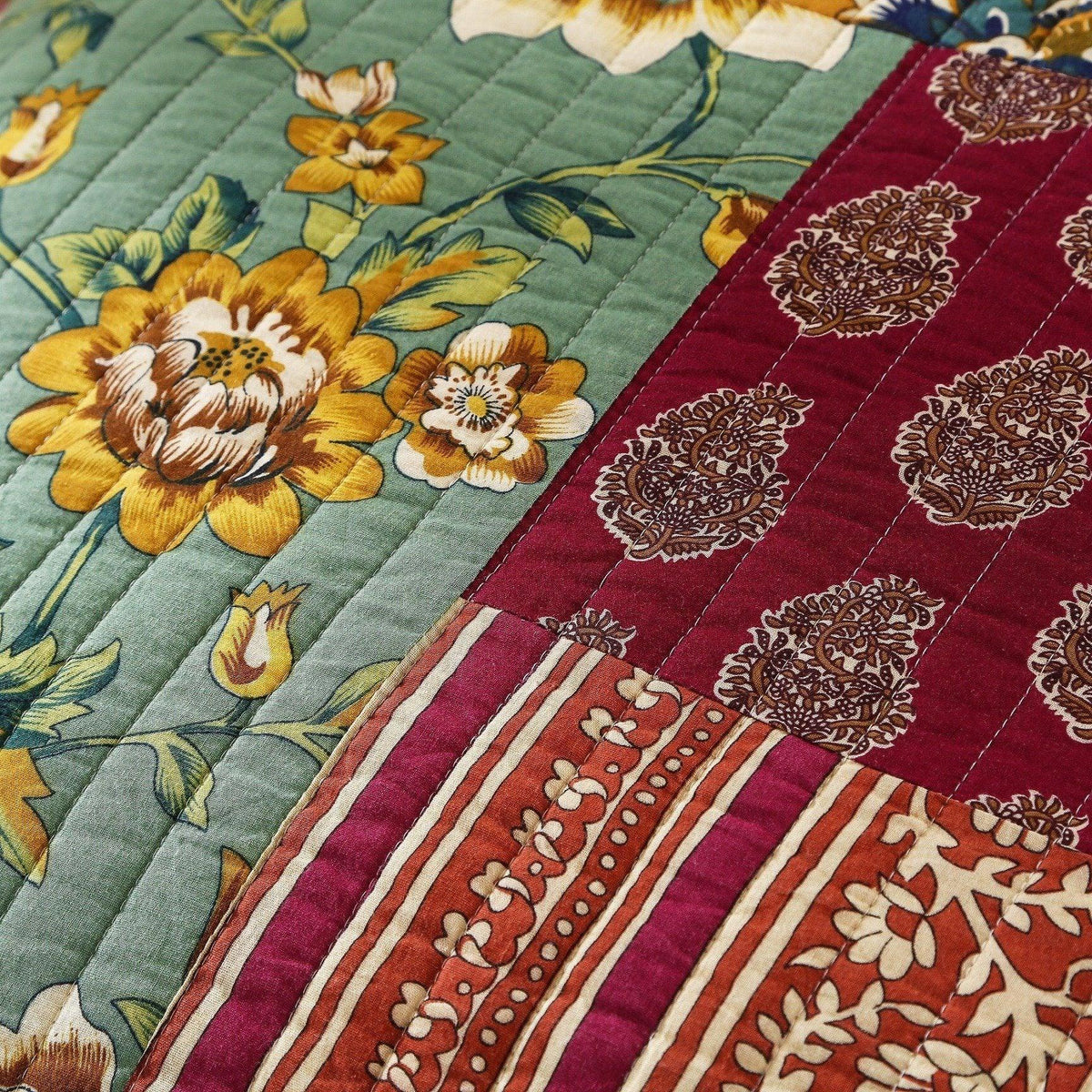 Quilted floral cotton patchwork bedspread corner with green and maroon sections