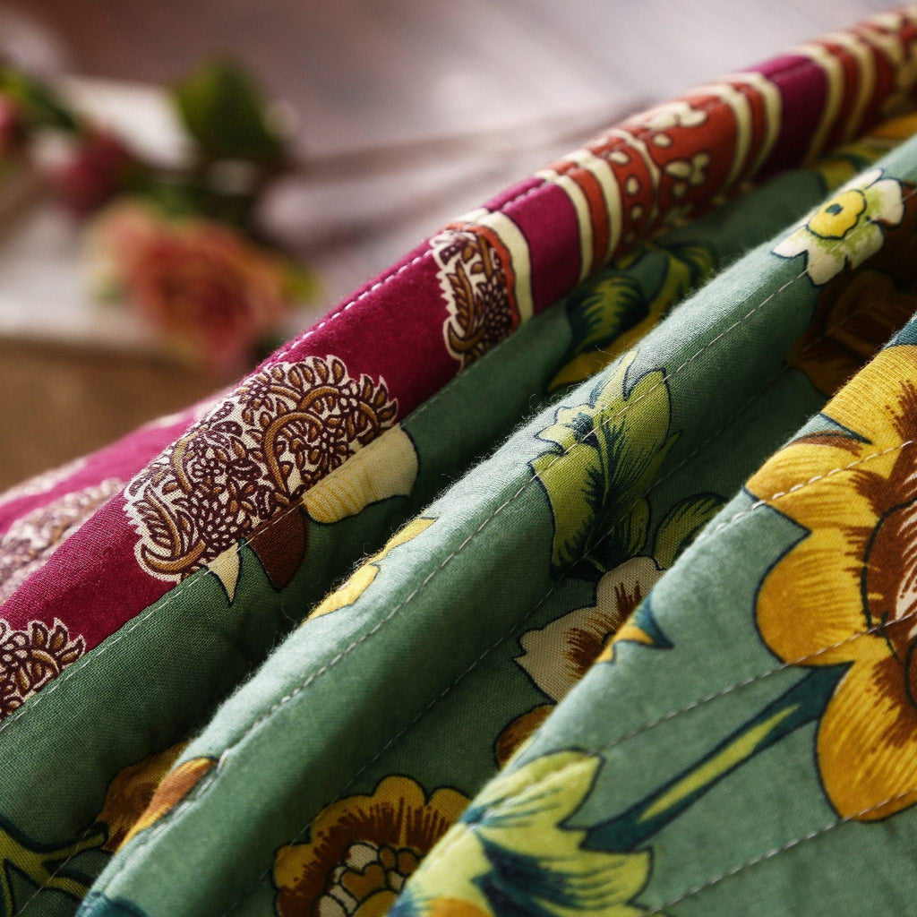 Cotton patchwork bedspread detail with green, maroon, and yellow floral stripe stitching