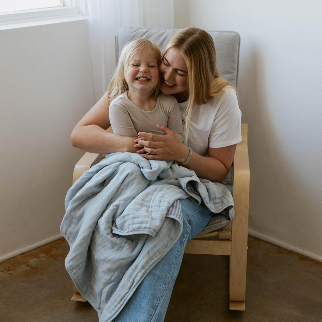 Light blue muslin quilt wrapped around child while being held by adult