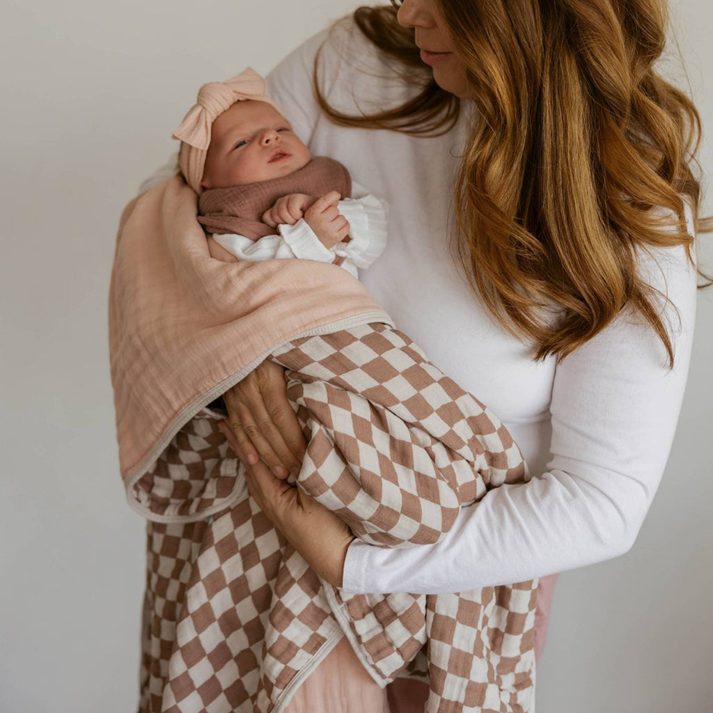 Checker-pattern baby quilt in rosewood squares with light pink trim, folded