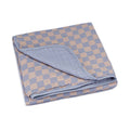 Folded blue-and-tan checker muslin quilt with rounded stitched edge