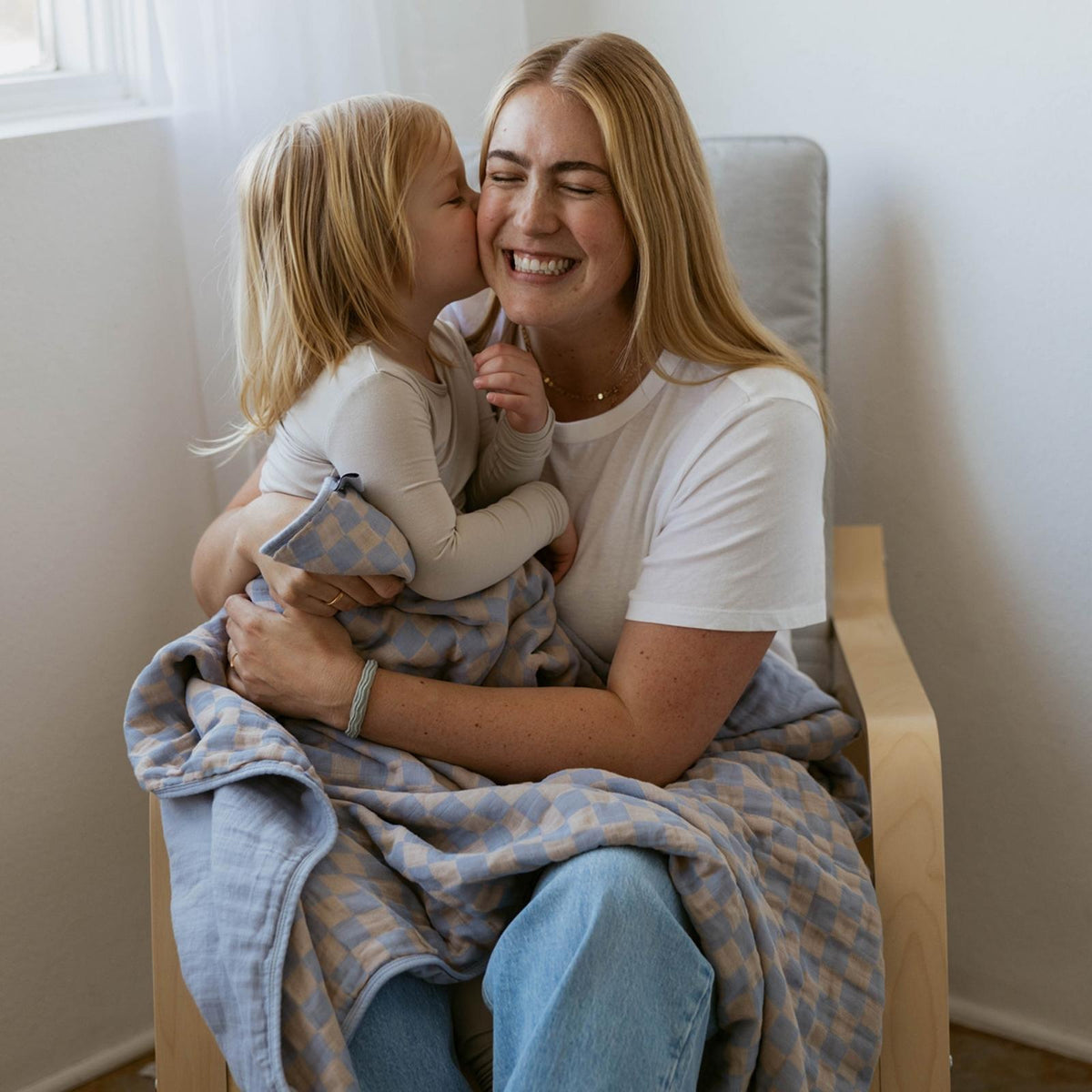 Blue-and-tan checker blanket wrapped around baby in caregiver arms