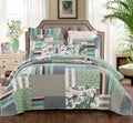 Quilted patchwork bedspread and pillows with teal, green, and cream botanical designs