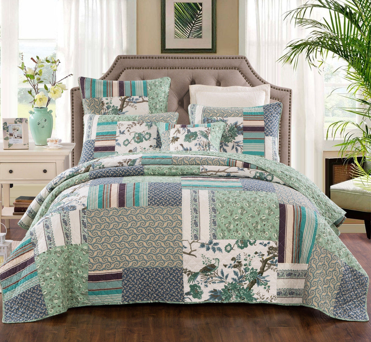 Quilted patchwork bedspread and pillows with teal, green, and cream botanical designs