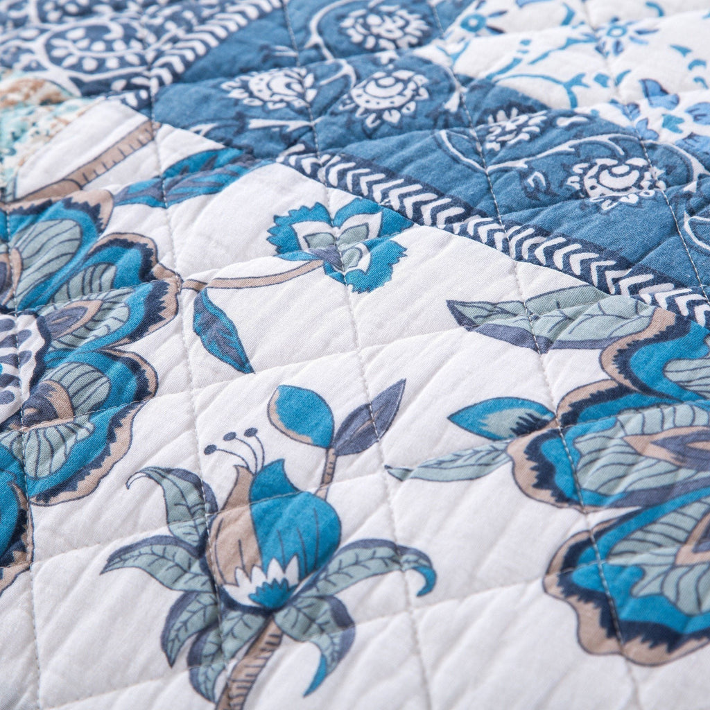 Close-up of blue and white floral quilt stitching with stitched patchwork pattern