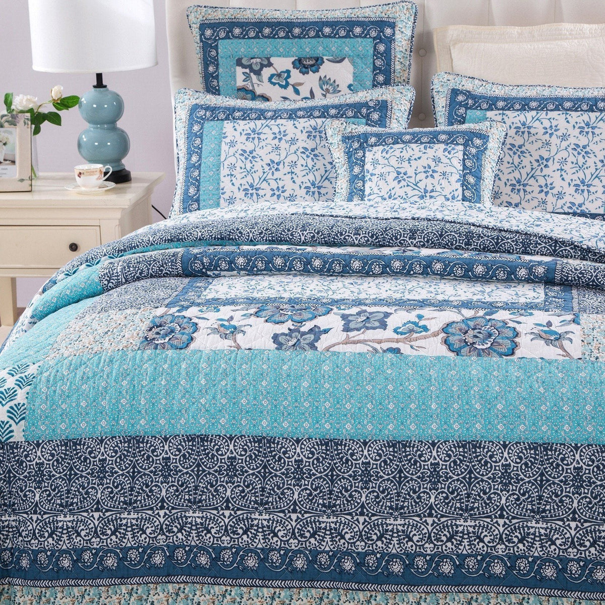 Blue patchwork quilt set with layered floral and border patterns across bed