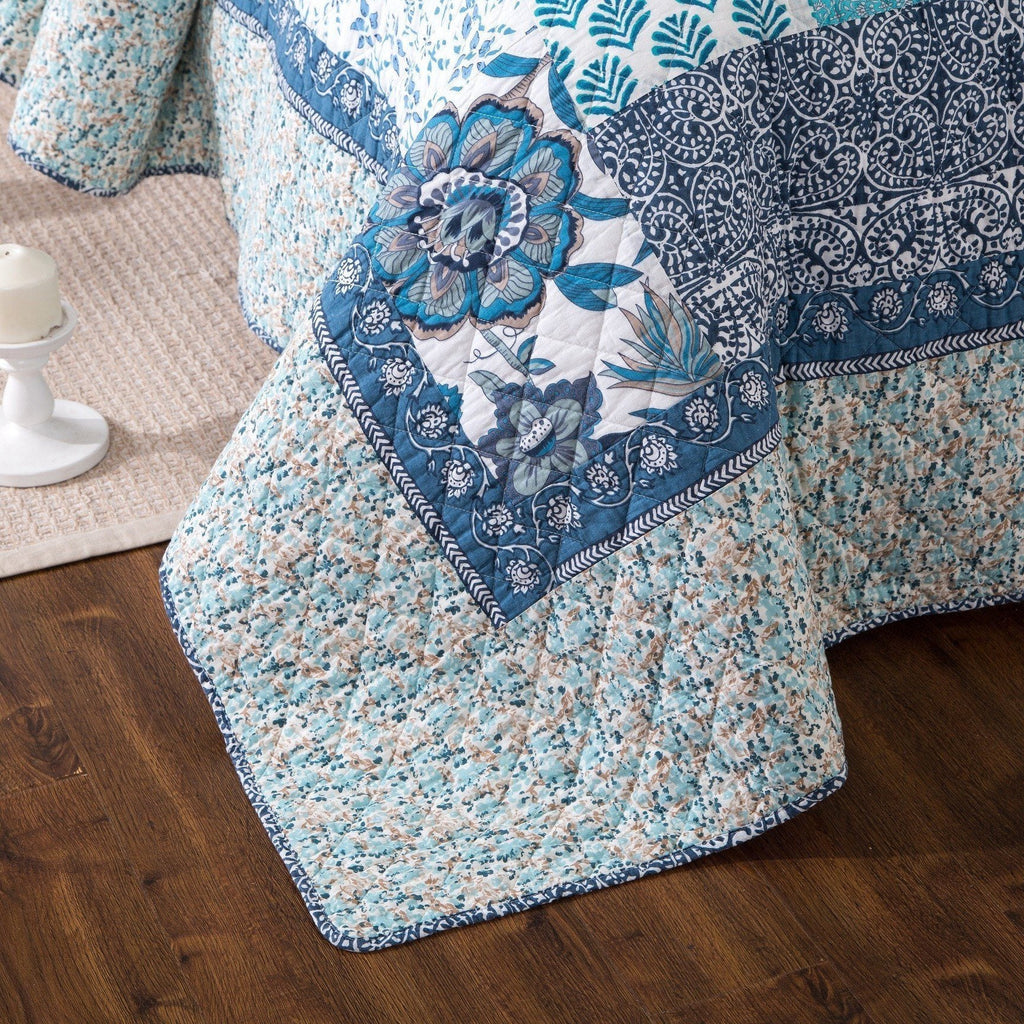 Blue floral quilt corner with stitched edge trim and patterned patchwork panels