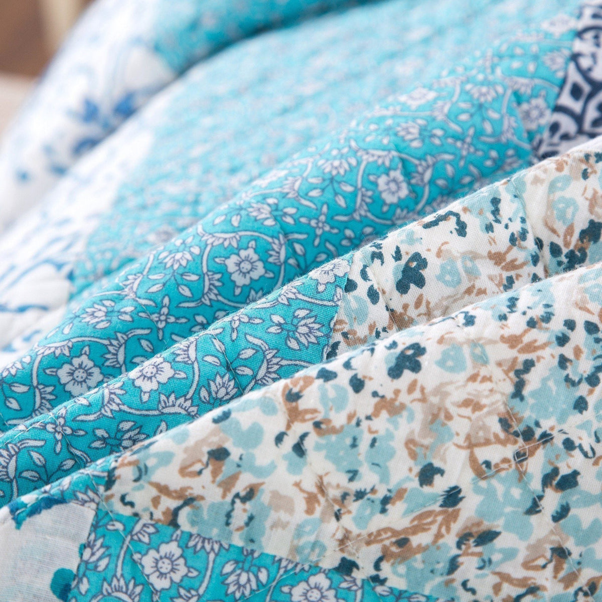 Blue quilt fabric close-up with layered floral prints and patchwork seams