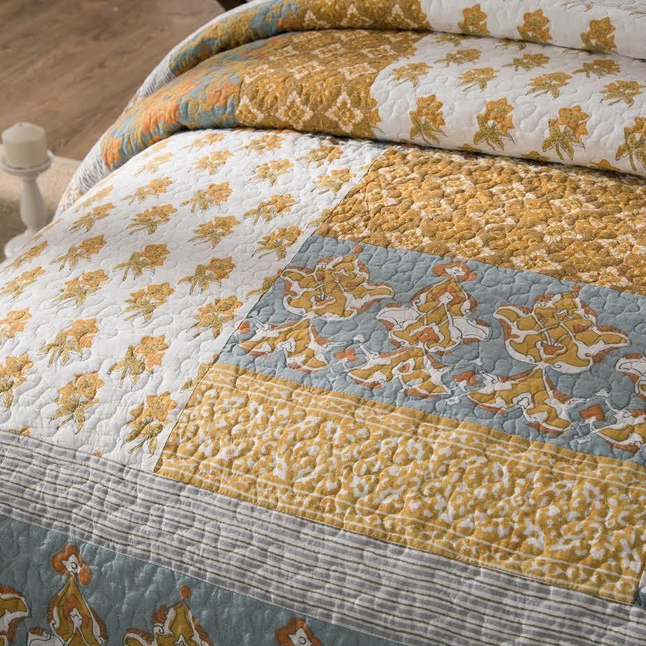 Cotton quilt bedspread with light blue, white, and gold floral-and-horse medallion pattern