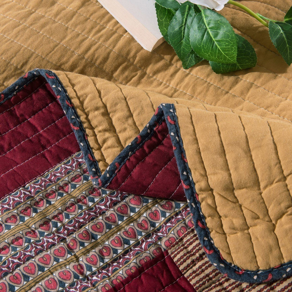Close-up quilt corner with maroon stitched sections and blue-edged floral trim