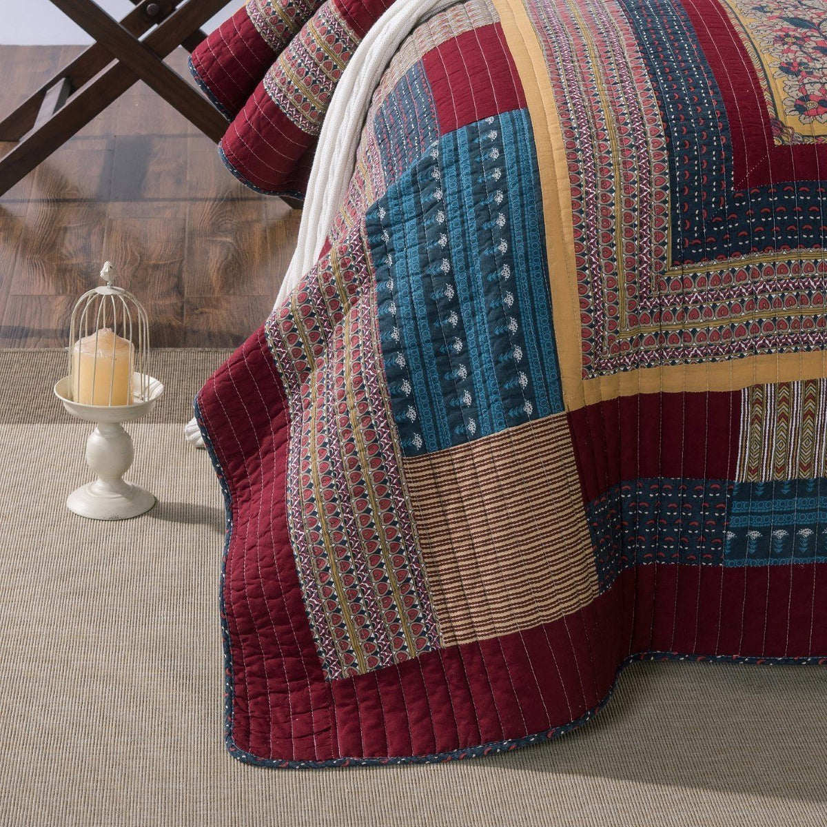 Patchwork quilt bedspread with bordered floral patterns in teal, red, and tan blocks