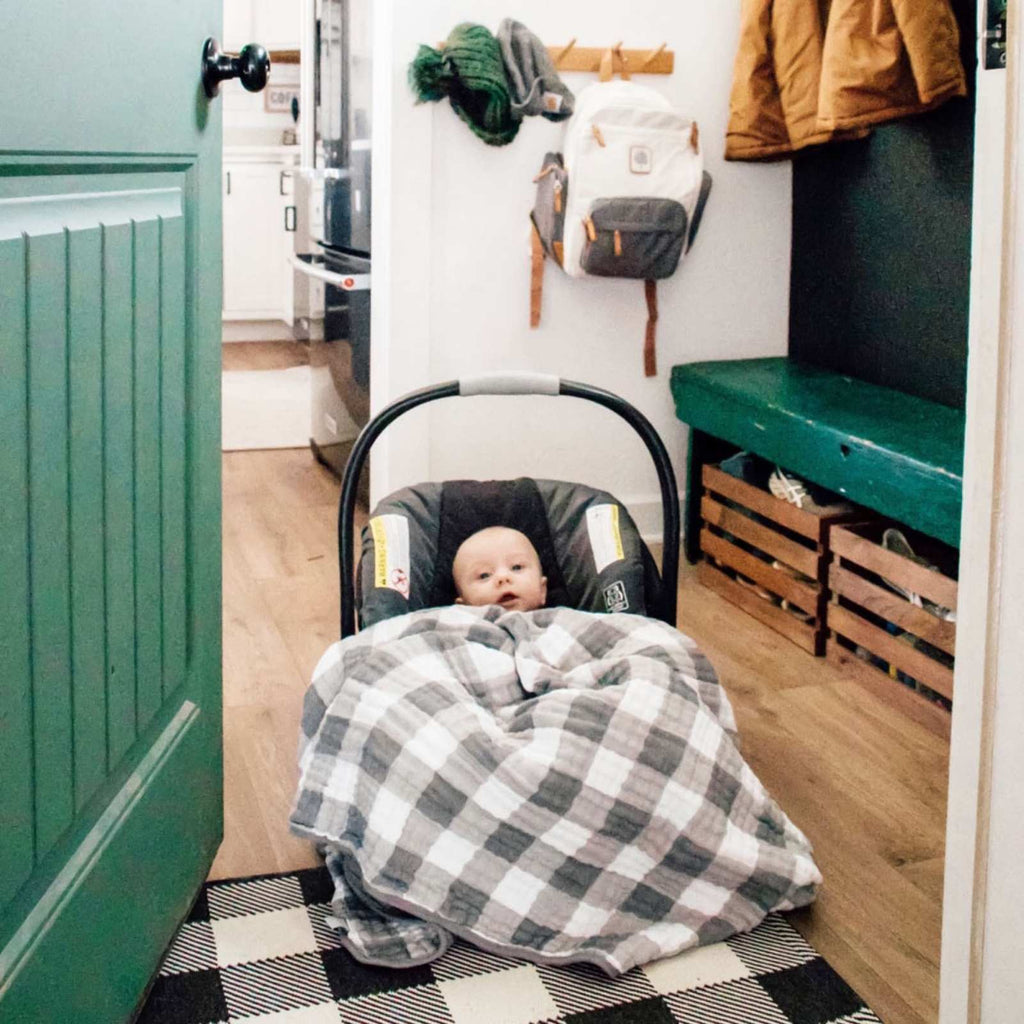 Gray and white plaid quilt wrapped around a baby in a car seat
