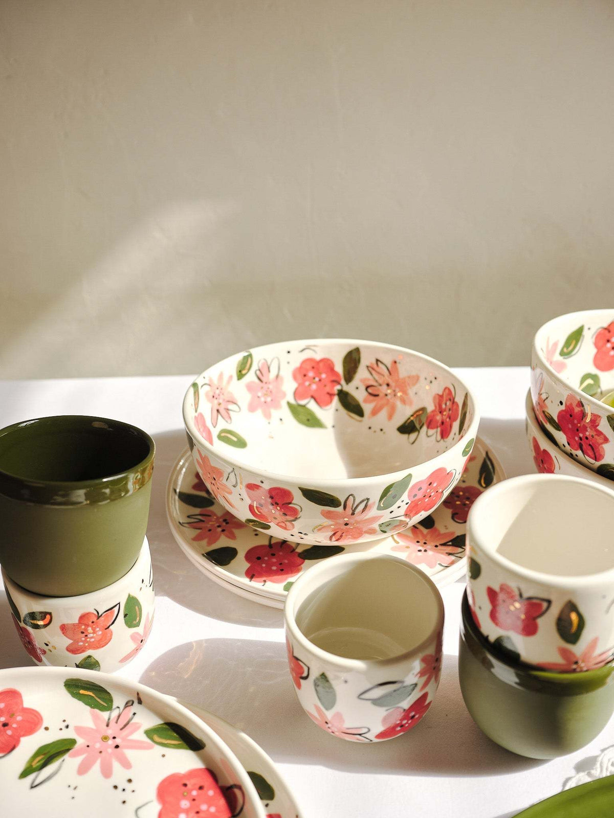 Hand-painted floral porcelain bowl with matching small cups and dishes on display