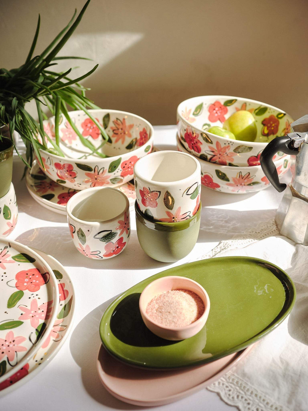 Porcelain floral salad bowl with matching cups beside a green serving dish