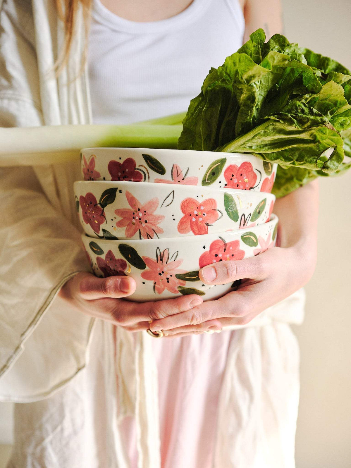 Porcelain salad bowl stack with hand-painted pink and red floral design, held in hands