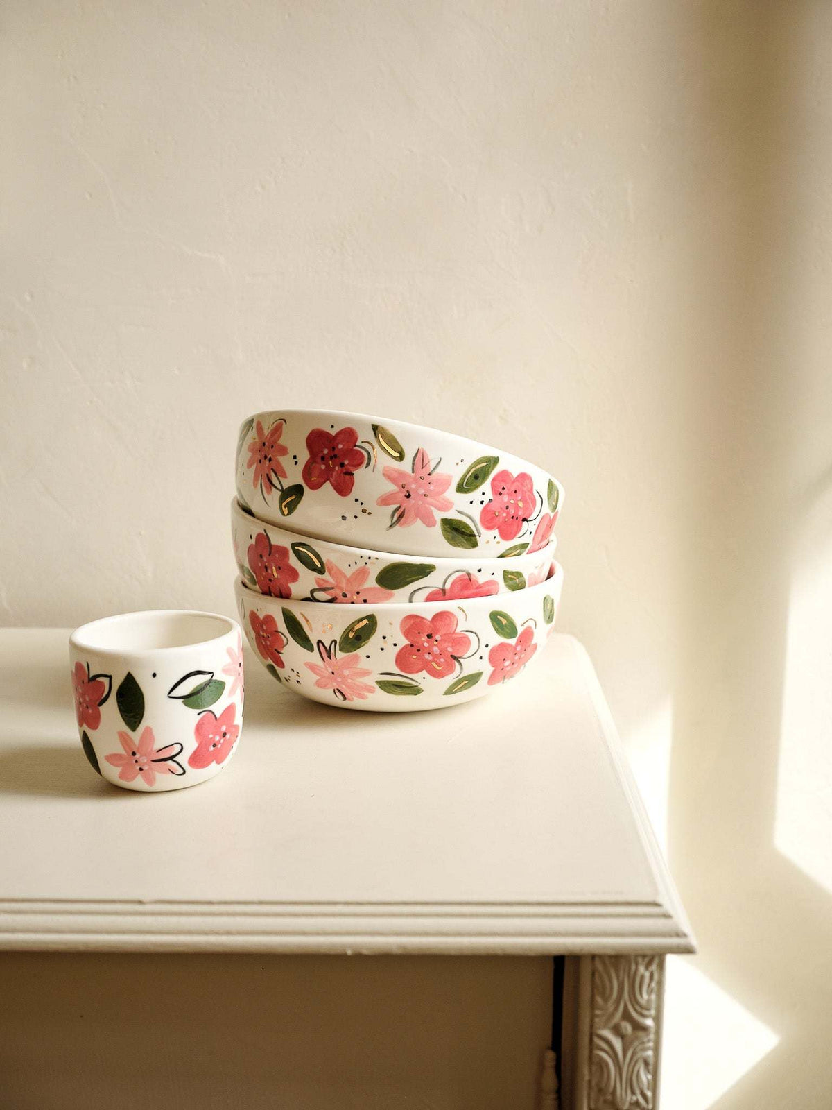 Stack of white porcelain salad bowls with hand-painted pink and red floral motifs