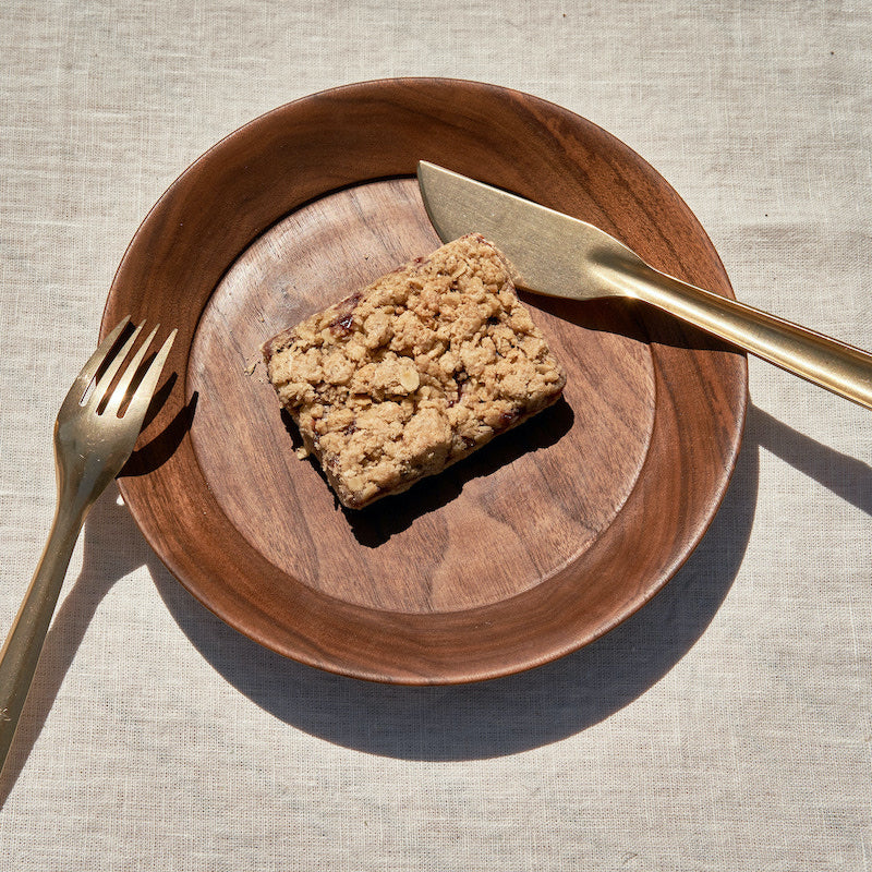 Raspberry oat bar on wooden plate with fork and knife