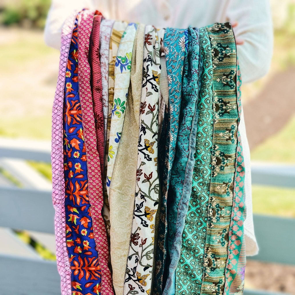 Stack of multicolor patchwork scarves in red, white, and teal with patterned bands.