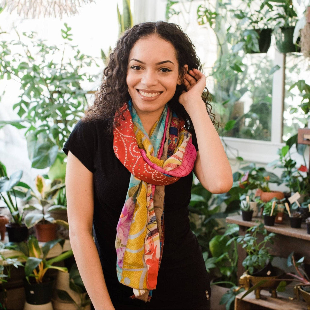 Orange and teal patchwork scarf with yellow and purple floral motifs worn by woman.