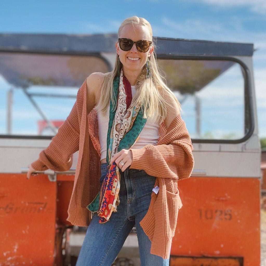 Woman wearing a multicolor patchwork scarf with teal and red accents.
