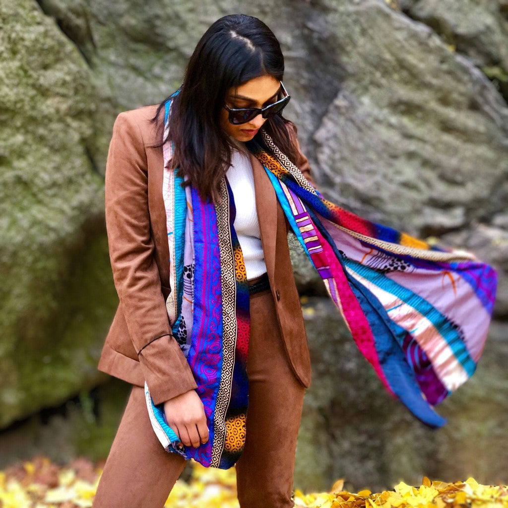 Multicolor patchwork scarf worn under a brown jacket with blue and pink accents.