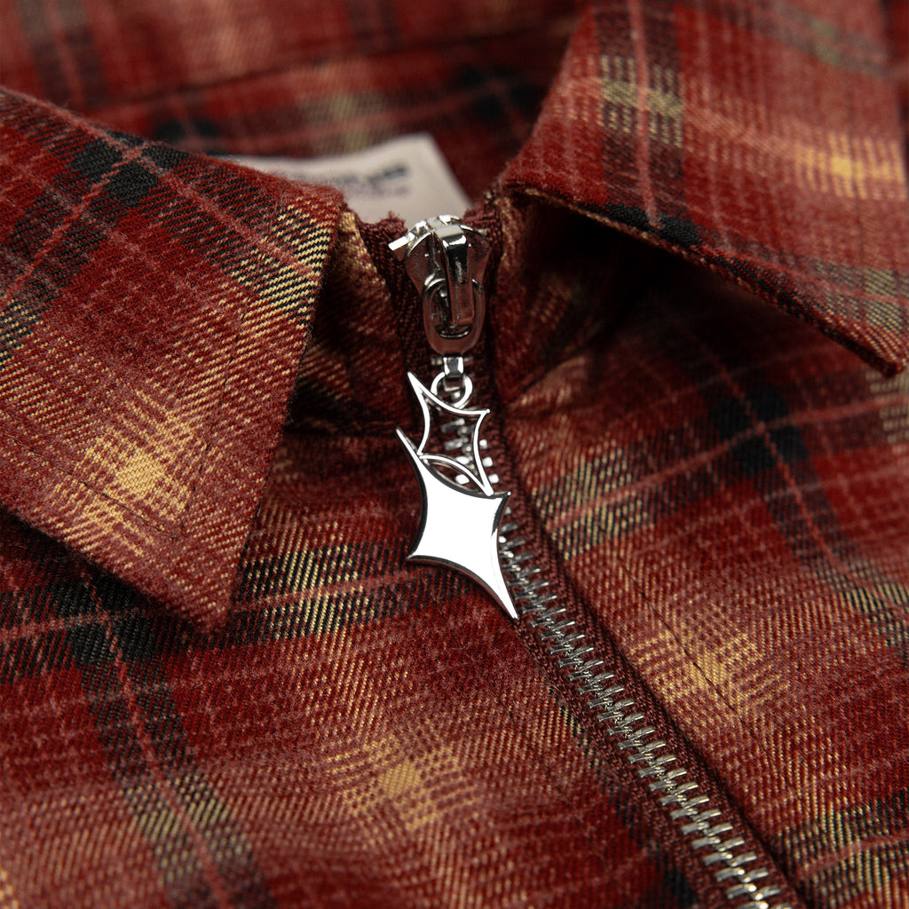 Close-up of red plaid flannel zipper pull with metal emblem charm