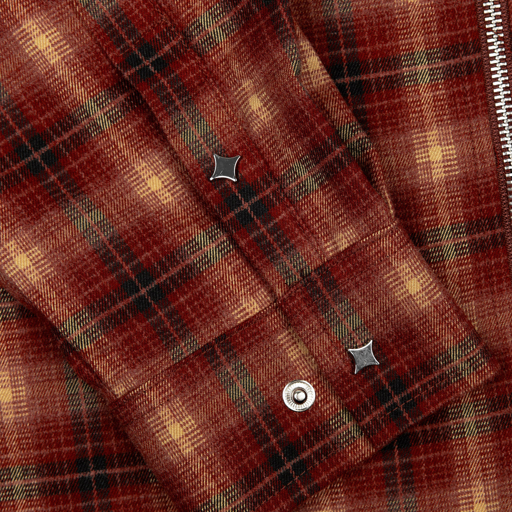 Close-up of red plaid flannel with metal zipper track and snap details