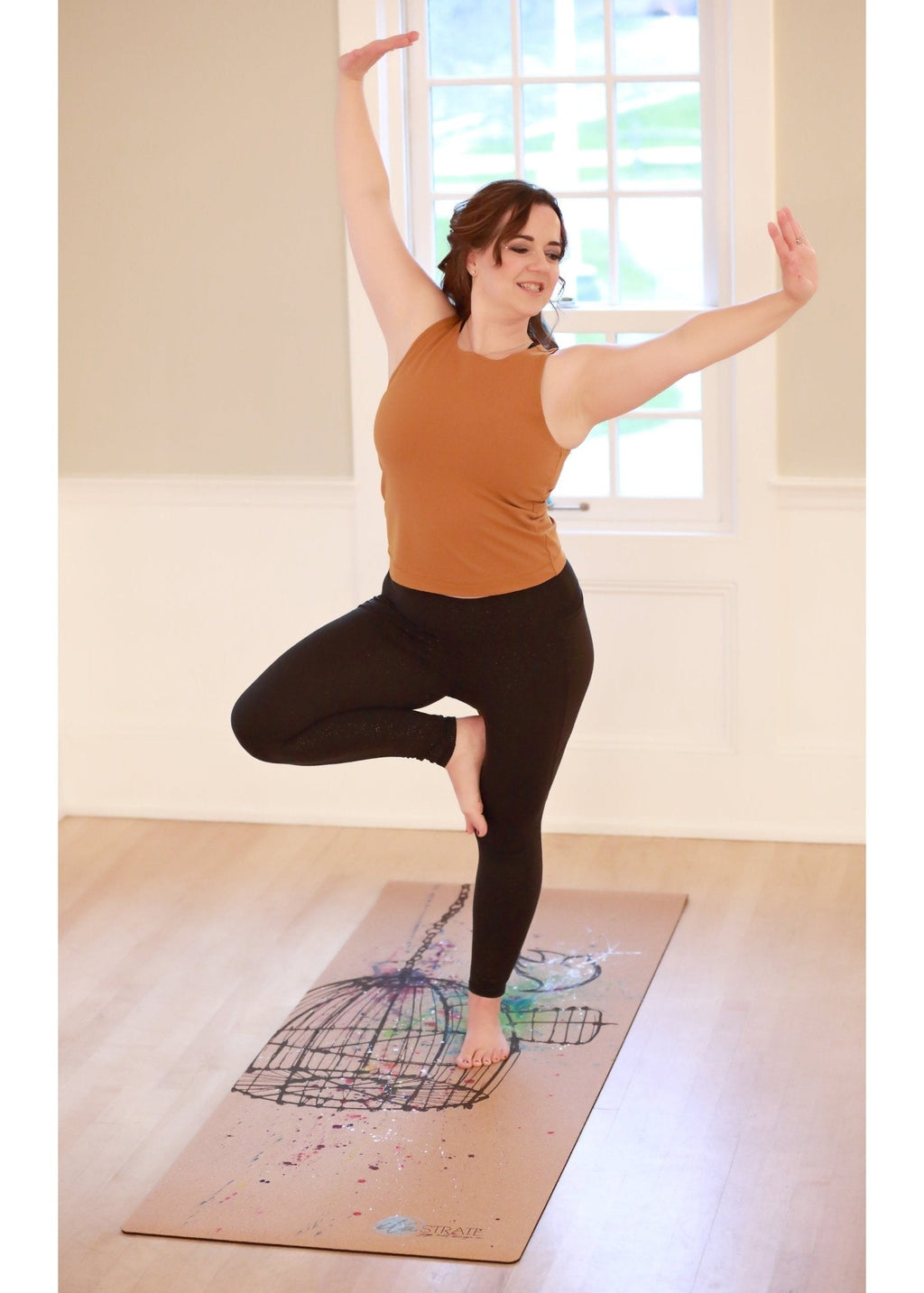 Cork travel yoga mat with birdcage artwork, shown in use for a yoga pose