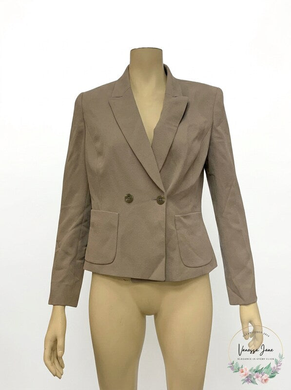 Grey peak-lapel blazer on mannequin, tailored single-breasted with two flap pockets.