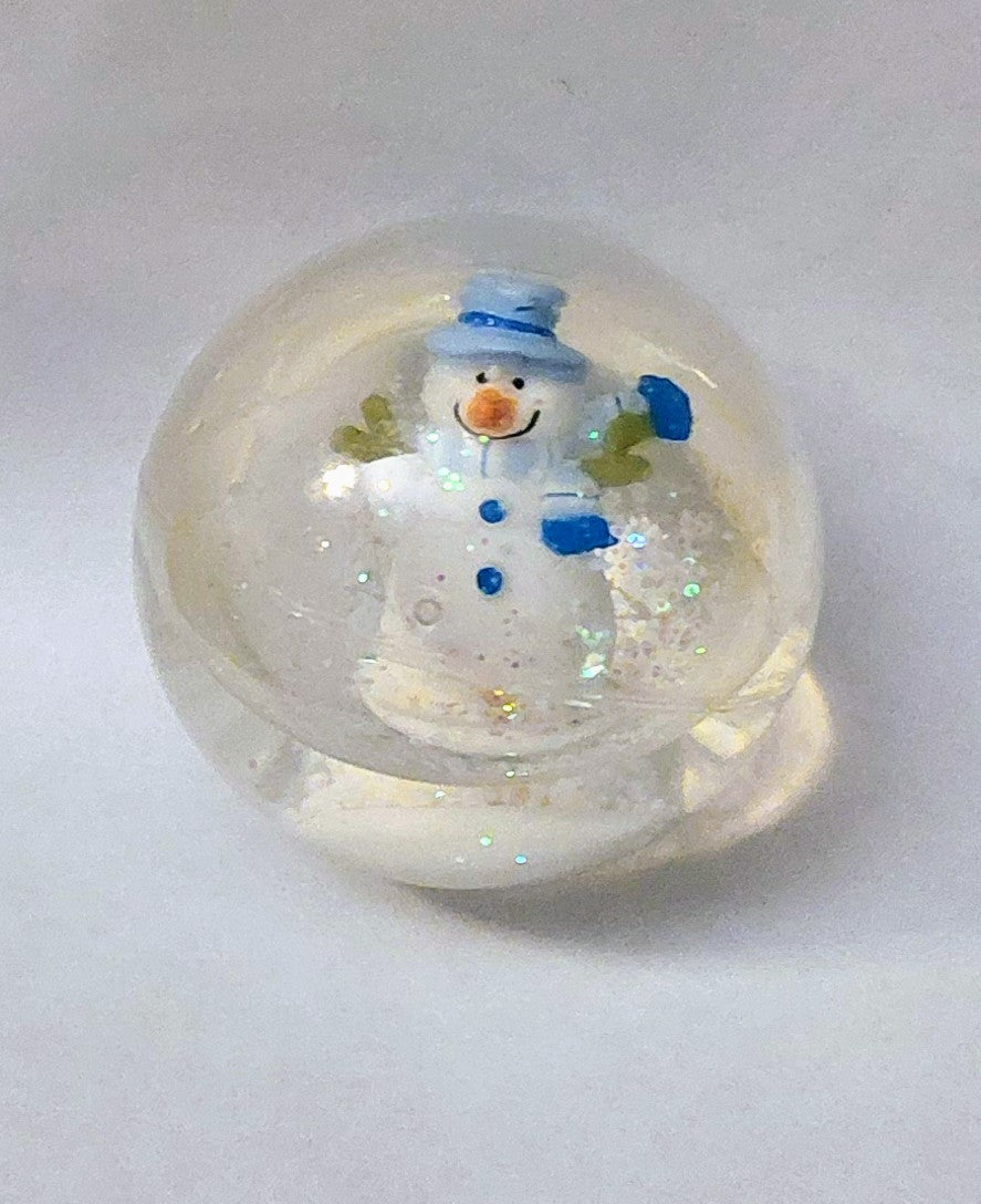 Snowman snow globe with blue hat and scarf inside clear glass globe
