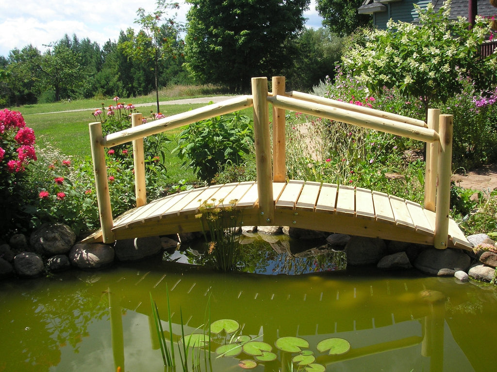 Wooden garden bridge with handrail and planked deck over pond water
