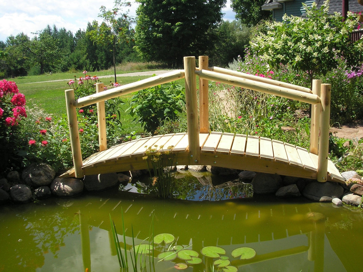 Wooden garden bridge with handrail and planked deck over pond water