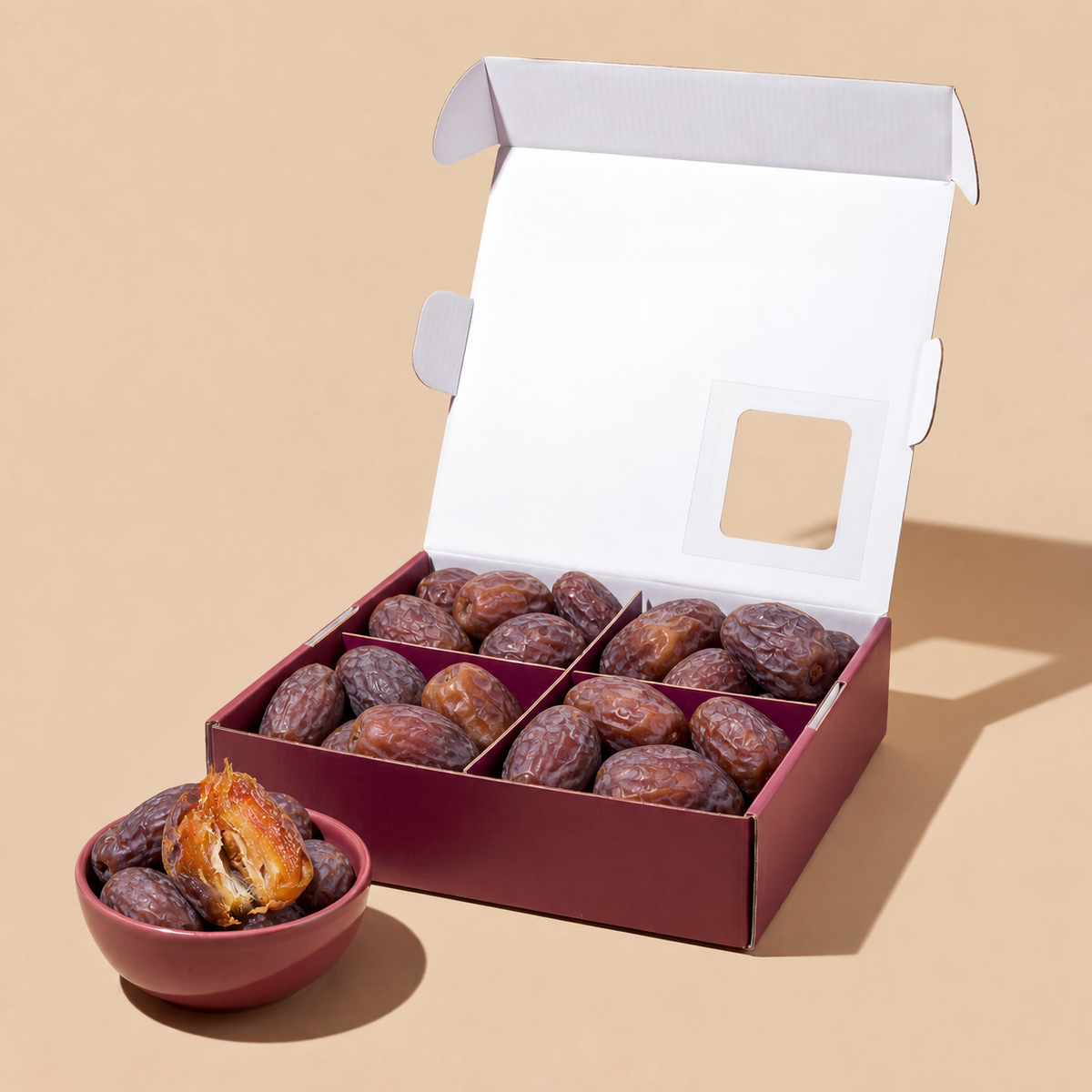 Open date box with dark purple Medjool dates and a small bowl of split date