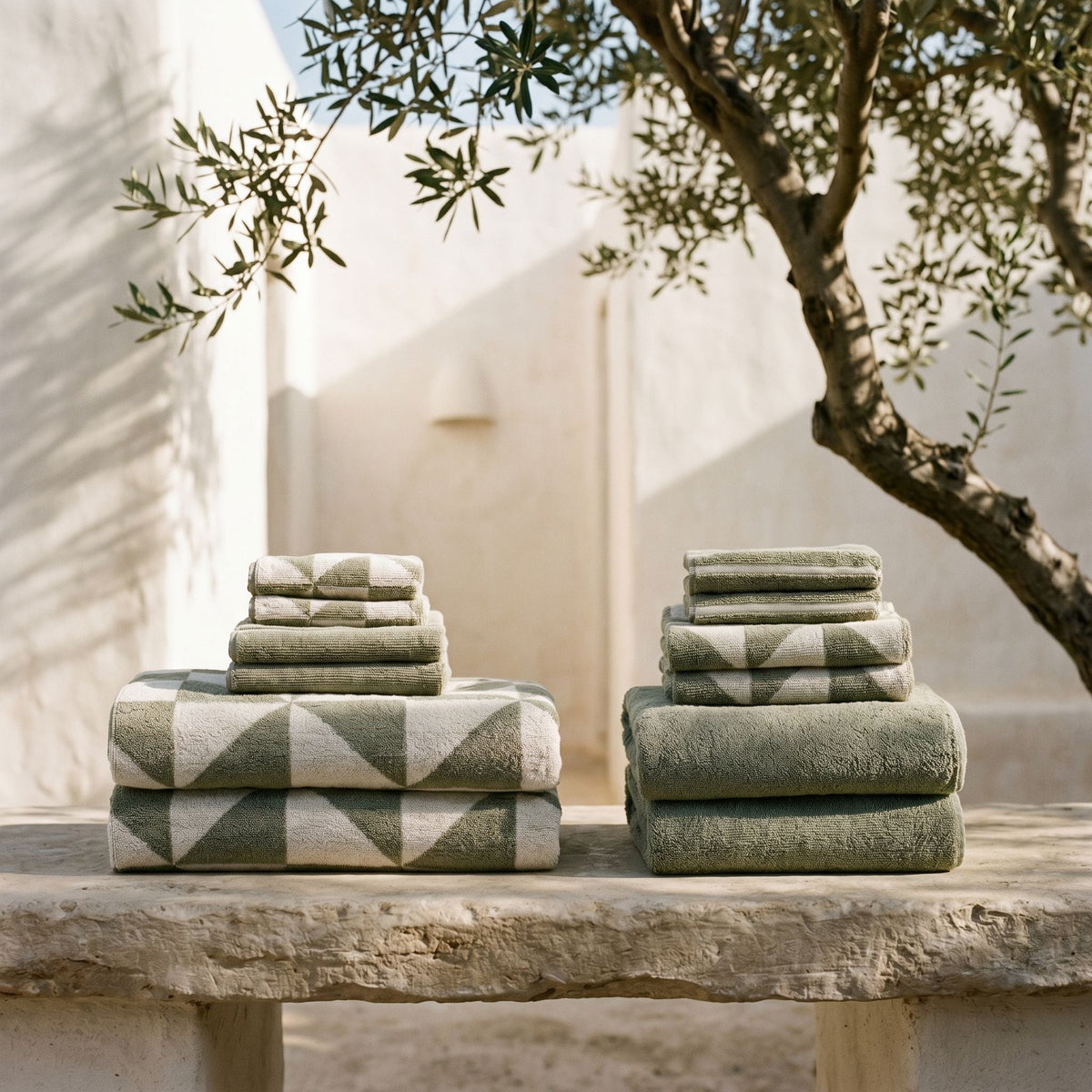 Stacked green towels with light geometric pattern bands on a ledge