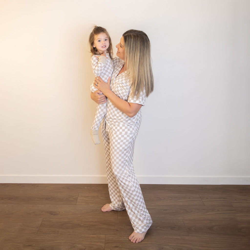 Adult holding child in matching checkered zippy coveralls with front zippers; beige and white